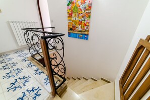 A staircase with a metal railing, a tiled floor with a blue pattern, and a colorful painting on the wall. - Casa Bouganville in Positano (Positano)