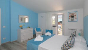 A bedroom with a bed, a dresser, a chair, a window, and a door leading to a balcony. - Relais Villa Chiara in Sorrento (Sorrento)