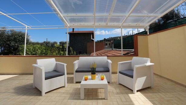 A covered outdoor seating area with two white wicker sofas and a small table, featuring a view of the surrounding landscape. - Relais Villa Chiara in Sorrento (Sorrento)
