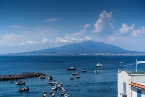 A coastal view with boats, a rocky pier, and a mountain in the background. - Casa Cinzia - Apartment (Vico Equense)