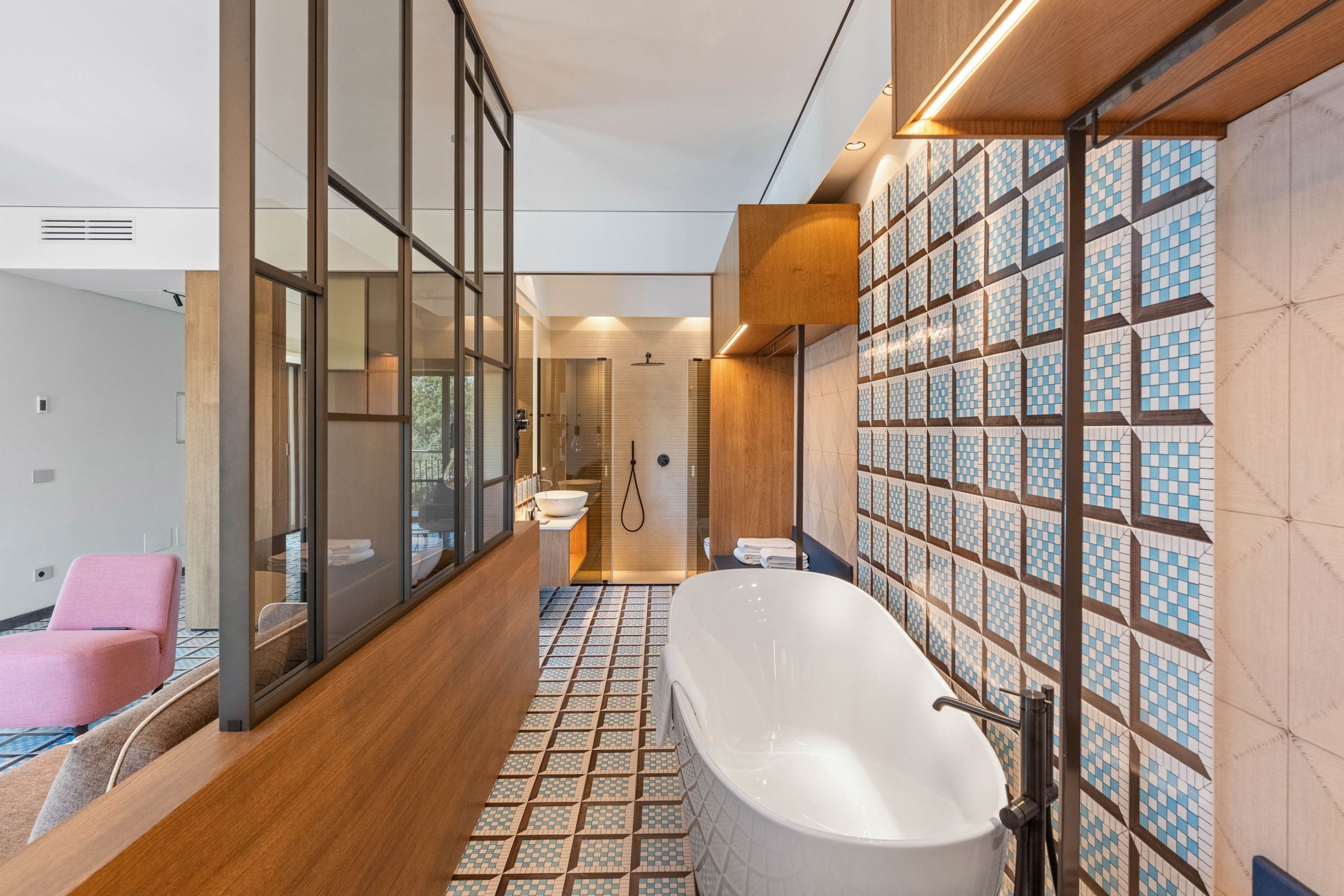 Un baño moderno con una bañera independiente, zona de ducha con mampara de cristal y suelo estampado.