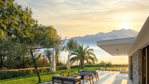 Una terrazza esterna con posti a sedere, vista sulle montagne e cielo sereno.