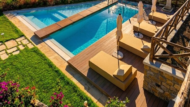 Una piscina con vista sul mare, circondata da vegetazione e montagne.