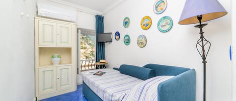 A compact room with a bed, a wardrobe, a TV, and a lamp.
