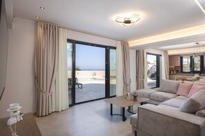 Ein modernes Wohnzimmer mit einer großen Couch, einem Couchtisch und Blick auf einen Pool und einen Außenbereich.