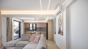 A modern living room with a sectional sofa, a dining area, and a kitchen in the background. - Villa Azure Luxury Sea View Villa (Mylopotamos)