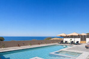 A swimming pool with lounge chairs and umbrellas, overlooking a body of water. - Villa Selene Luxury Sea View Villa (Mylopotamos)