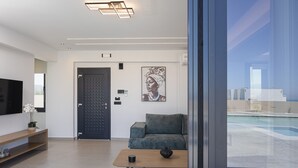 A modern living room with a sofa, a coffee table, a TV, and a painting on the wall. - Villa Selene Luxury Sea View Villa (Mylopotamos)