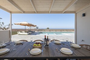 Ein Esstisch für sechs Personen mit Blick auf Pool und Meer.