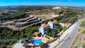 Una villa con piscina, una strada e campi a terrazze sullo sfondo.