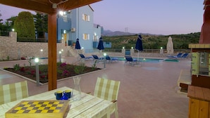 Area piscina con sedie a sdraio, un tavolo da scacchi e vista su un edificio con piscina.