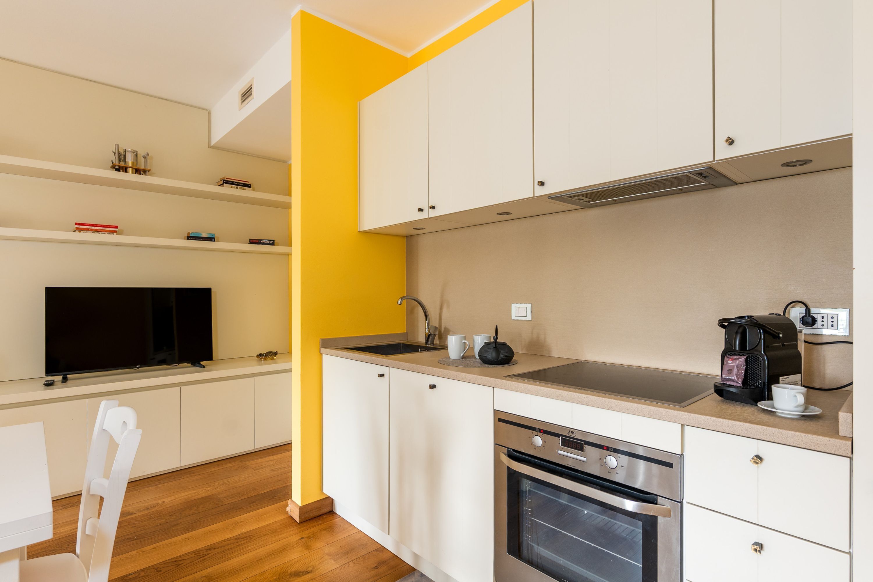 A modern kitchen with white cabinets, a stainless steel oven, and a coffee maker.