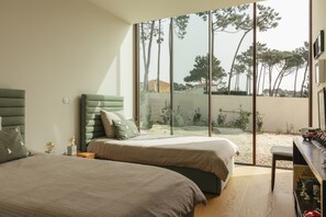 A bedroom with two beds, a large window, and a view of trees and buildings. - Moon Forest Retreat by Cadenzalux (Sintra)