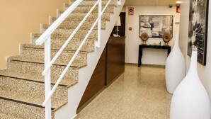 A staircase with white railings leading to a landing, a reception desk, and a wall with framed artwork.