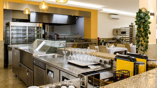 A modern kitchen with stainless steel appliances, a large sink, and hanging pendant lights.