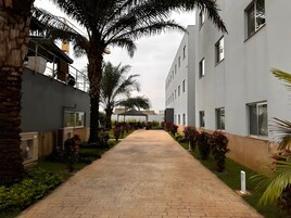 Un camino conduce a un edificio de diseño moderno, rodeado de vegetación y palmeras.