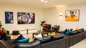 A modern living room with a black leather sofa, a flat-screen TV, and a coffee table.