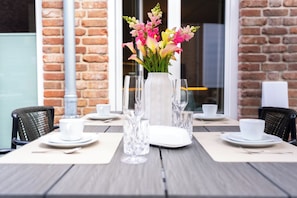 Ein Tisch für zwei Personen, gedeckt mit Blumen, klarem Glas und weißen Tellern und Tassen.