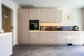 A modern kitchen with built-in appliances, a coffee machine, and a decorative compass wall art. - MeerNah love. Terrace. Close to the beach. Infrared cabin. (Grömitz)