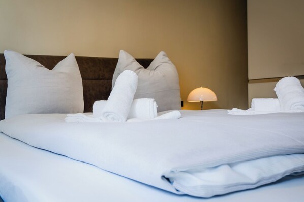 A neatly made bed with pillows and towels, a bedside lamp, and a headboard. - MeerNah love. Terrace. Close to the beach. Infrared cabin. (Grömitz)