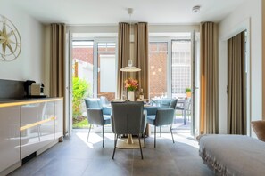 A modern bedroom with a bed, a desk, and a dining area with chairs and a table. - MeerNah love. Terrace. Close to the beach. Infrared cabin. (Grömitz)