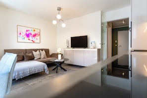 A modern living room with a sofa, a coffee table, a flat-screen TV, and a glass door leading to a kitchen. - MeerNah love. Terrace. Close to the beach. Infrared cabin. (Grömitz)