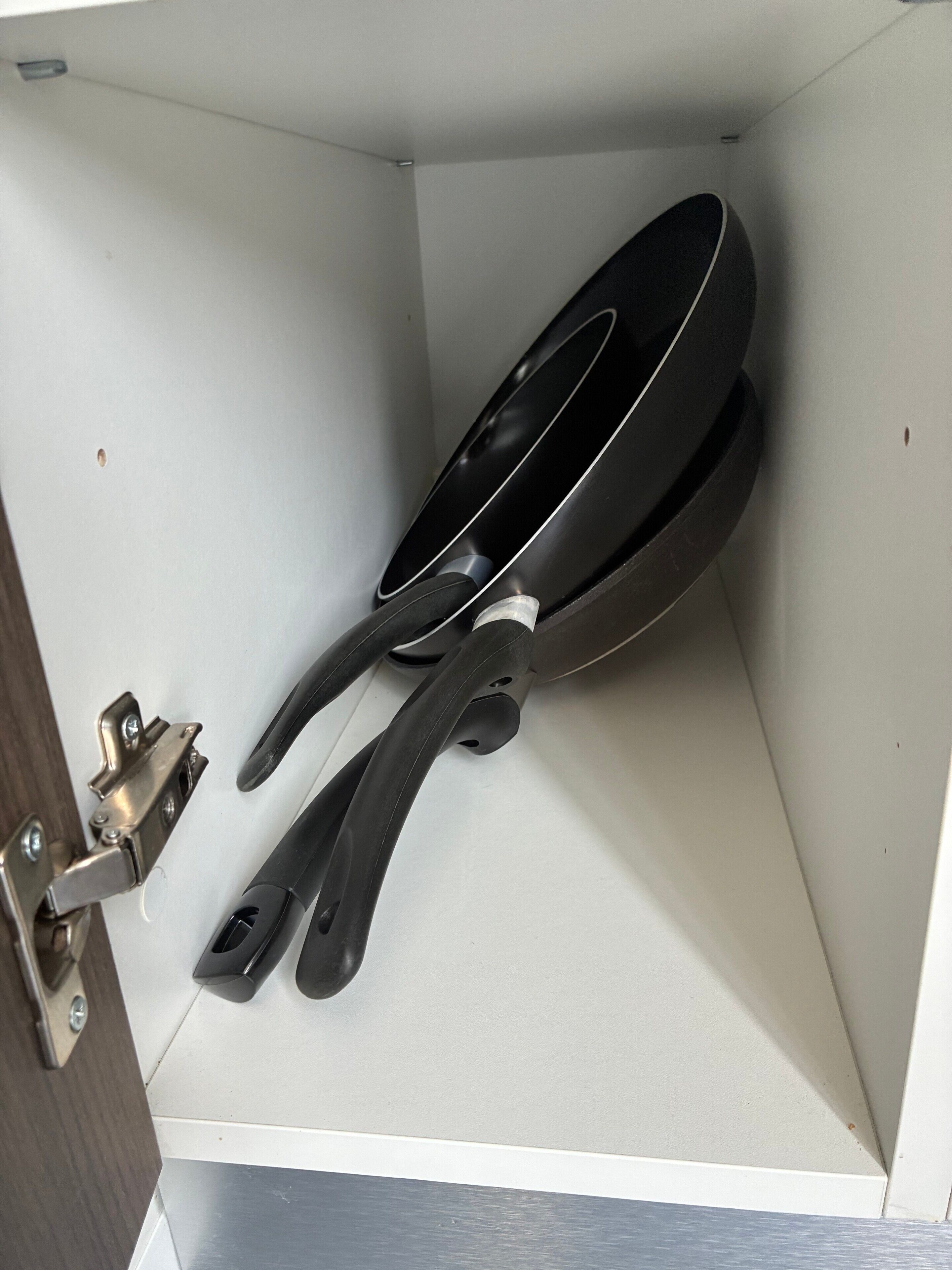 A kitchen with a white countertop, a black frying pan, and a metal handle.