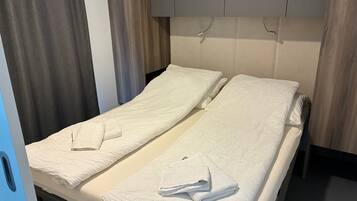 A hotel room with a bed, two towels, a curtain, and a wooden headboard.