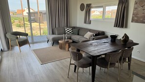 Un salon moderne avec un canapé, une table à manger, des chaises et une vue dégagée grâce à de grandes fenêtres.