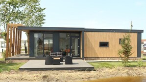Un bâtiment moderne avec une entrée en verre, des places assises en plein air et une façade en bois.