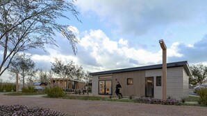 Een modern gebouw met een plat dak, grote ramen en een persoon die buiten loopt.