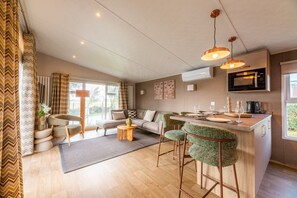 A modern kitchen with a microwave, bar stools, and a dining area. - Experience the Strandrust Lodge at Holiday Park Blankenberger Duinen at any time of the year. Enjoy a carefree holiday with the whole family. (De Haan)