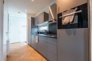 Eine moderne Küche mit grauen Schränken, einer schwarzen Dunstabzugshaube und einem Fenster über dem Herd.