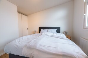Ein Schlafzimmer mit einem Bett, einem Nachttisch, einem Kleiderschrank und einem Fenster.