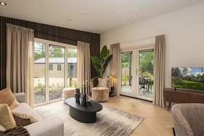 Ein geräumiges Wohnzimmer mit großem Fenster, bequemer Couch, Couchtisch und Fernseher.