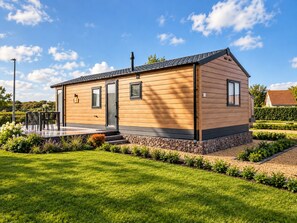 A modern wooden house with a covered patio, a chimney, and a well-maintained garden. - Enjoy your holiday in the Zeebries Cabin: a comfortable holiday home on the Flemish coast for 4 persons, fully equipped for a carefree stay. (De Haan)