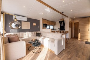 Ein modernes Wohnzimmer mit einer Eckcouch, einem runden Couchtisch und einem Essbereich mit kleinem Tisch und Stühlen.