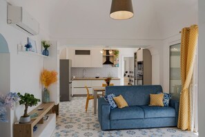 Ein modernes Wohnzimmer mit einer Couch, einem Essbereich und einer Küche im Hintergrund.