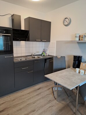 Eine moderne Küche mit einem Einbauofen, einer Kaffeemaschine und einer Wanduhr.