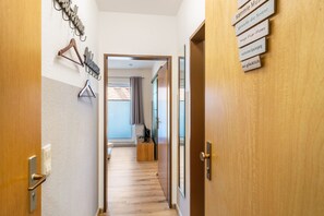 Un couloir avec des portes en bois, un porte-manteau et un panneau avec du texte.