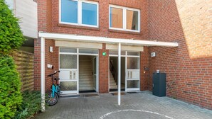 A building with a brick facade, a covered entrance, a bicycle, and a mailbox. - Apartment 'Fewo Strandweh in Dornumersiel' with Balcony and Wi-Fi (Dornum)