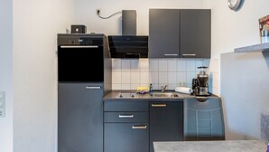 A compact kitchen with a built-in oven, a coffee maker, and a sink. - Apartment 'Fewo Strandweh in Dornumersiel' with Balcony and Wi-Fi (Dornum)