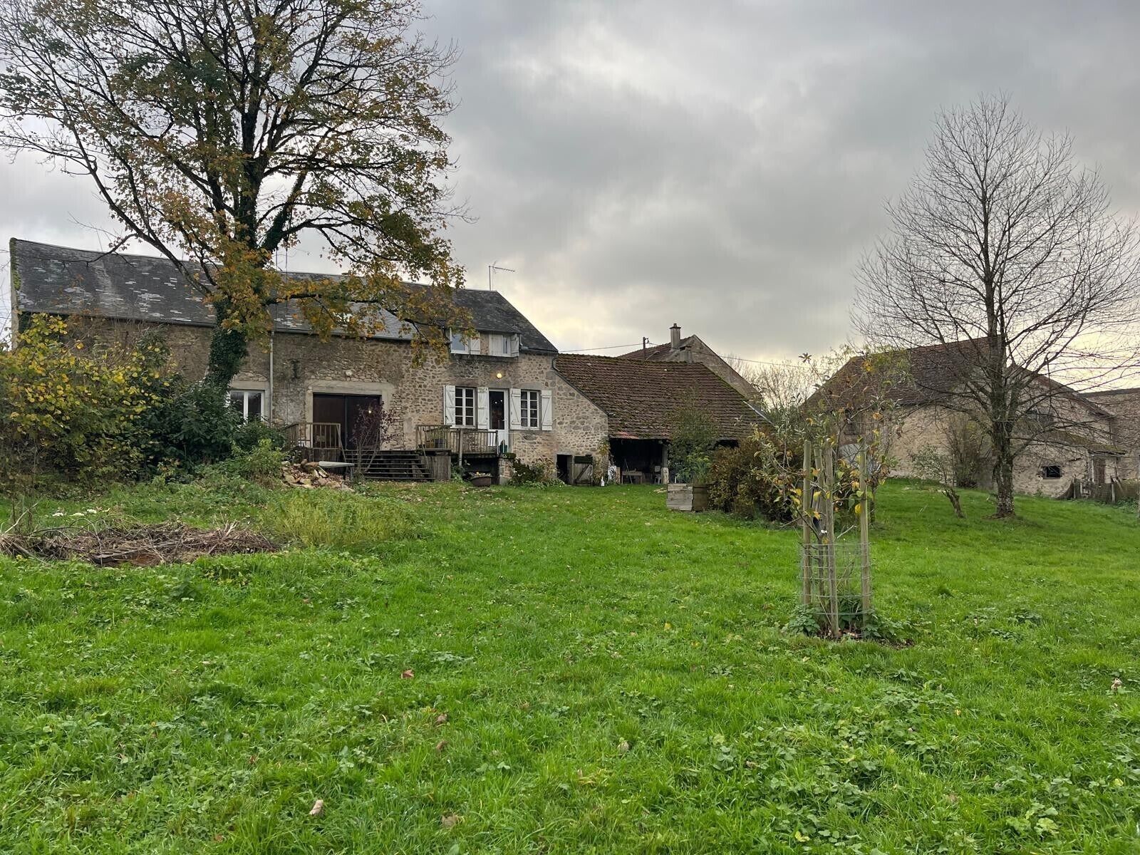 Een stenen boerderij met een ruime voortuin en een schuur.