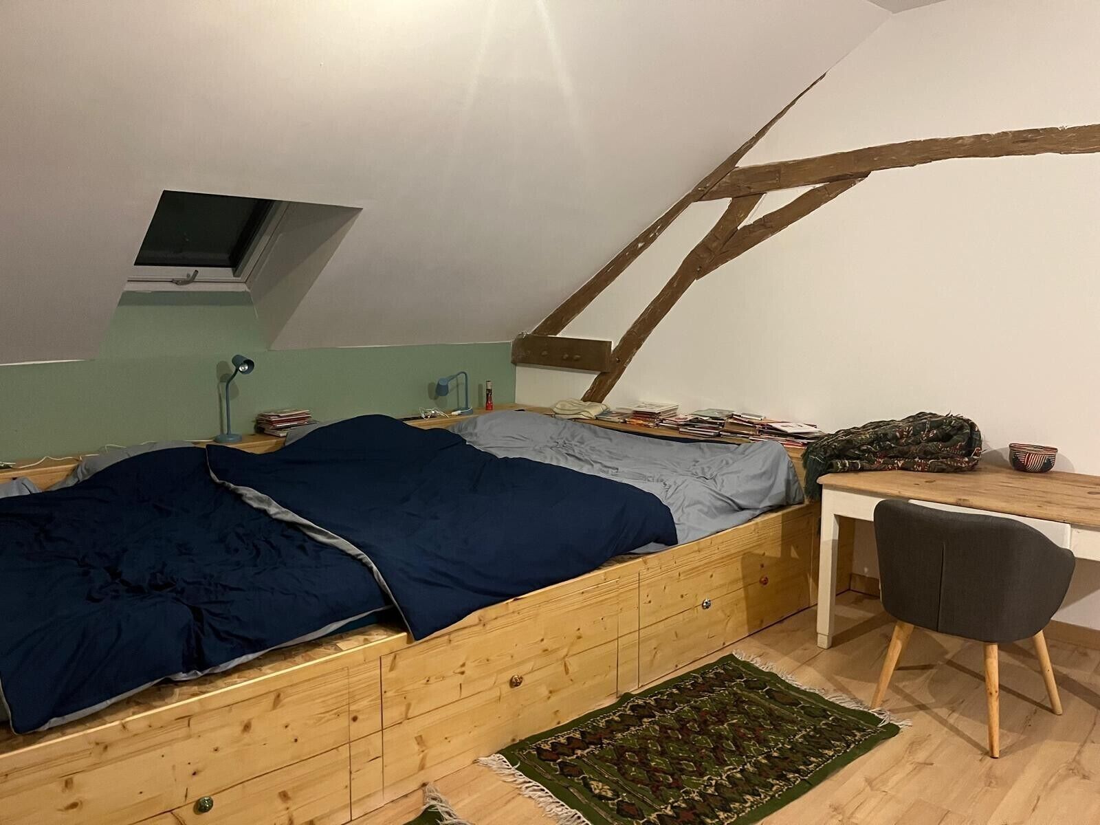 Een slaapkamer in loftstijl met een houten bed, een bureau en een stoel.