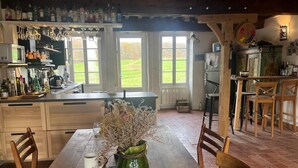 Uma cozinha rústica com uma mesa de madeira, cadeiras e um vaso de flores secas.