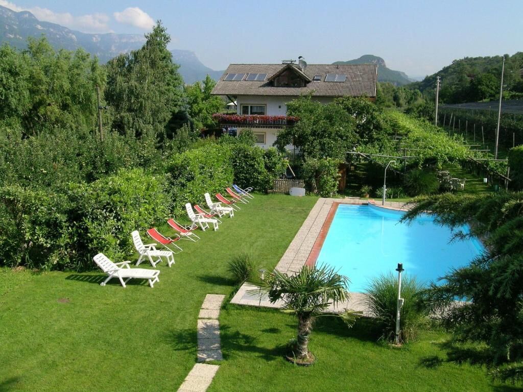 A pool with lounge chairs, a house, and a mountainous backdrop.