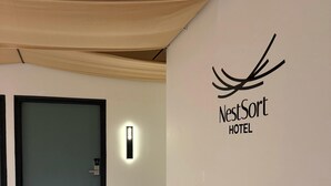 Un pasillo con el letrero NestSort Hotel, una puerta y una lámpara fijada a la pared.