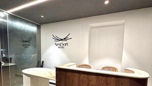 Un mostrador de recepción de NestSort Hotel con un diseño moderno, una pared de vidrio y un interior limpio y minimalista.