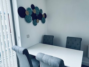 Un comedor moderno con una mesa blanca y sillas tapizadas en gris.