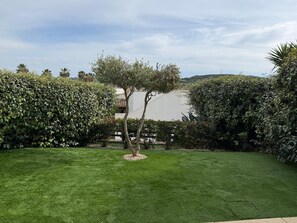 A well-maintained garden with a central tree, surrounded by neatly trimmed hedges and a grassy lawn. - Villa Corallo, entire villa 4km from Alghero with breathtaking views of Capo Caccia (Sardegna)
